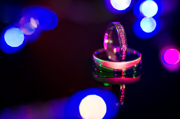 Wedding rings of white gold on a black shiny background.