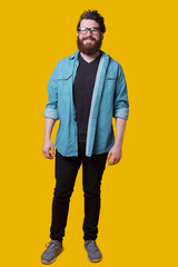 Fototapeta premium Full length photo of young bearded man standing over yellow background and looking at the camera