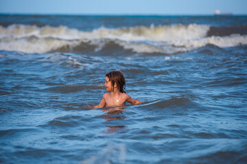 Kid boy playing and having fun on the beach on blue sea in summer. Travel lifestyle, swimming on sea summer camp.