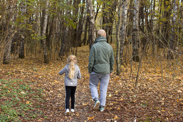 Man and girl walking in the autumn forest