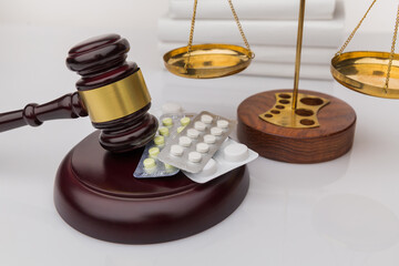 Drugs and law. Judge gavel and colorful pills on a wooden desk, dark background, closeup view.