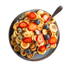 Pancake cereal. Heap of  mini pancakes with berries in gray bowl isolated on white.  Trendy food. Top view.
