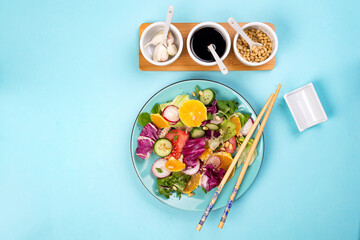Fresh vegetables salad with various dressing on blue background, top view, border.