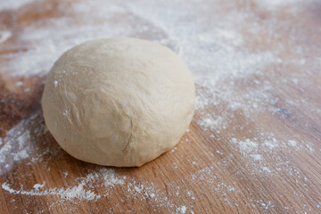 Ball of fresh yeast dough on floured table, resting before making pizza or bread