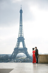 Fototapeta na wymiar man and woman in red dress and hat on Eiffel tower in Paris. symbol of France.