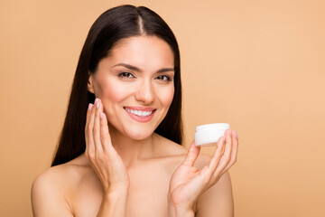 Closeup photo of mature nude lady toothy model natural beauty no makeup holding anti age cream bottle applying touch soft cheek isolated beige pastel color background