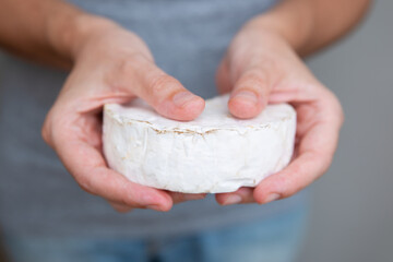 Hands holding soft cheese. Tasty brie or camembert. Studio shot. Selective focus. Front view. Dairy...