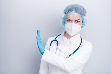 Photo of beautiful lady doc raise palm side stay away from covid dangerous infected zone vaccine research wear gloves mask coat facial plastic surgical cap isolated grey color background