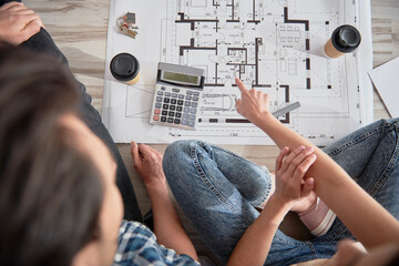 Top view of blueprint discussed by a couple