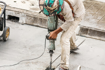 Construction worker using jackhammer drilling concrete surface