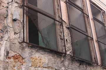 broken protection grate of a window of an ancient building with ruined wall in the historic center of Palermo in Italy