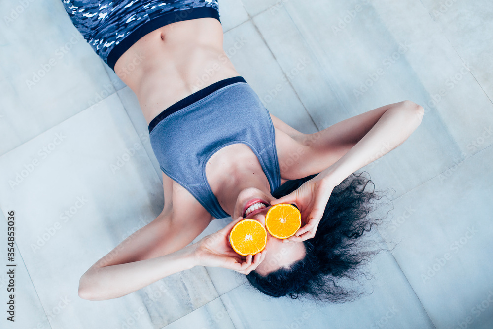 Wall mural fit woman being playful with two oranges