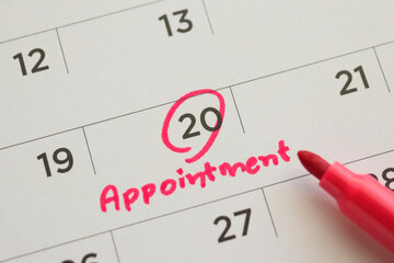 Red color marker pen pointing at important appointment schedule on white calendar page date close up