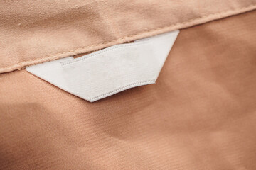 blank white clothing label on brown fabric texture background