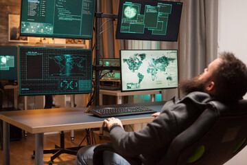 Bearded hacker leaning back on his chair while hacking credit cards all over the world.