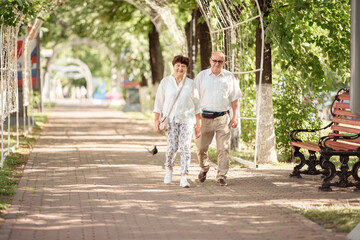 Happy grandparents and granddaughter having fun in summer park together