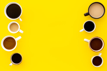 Cups of hot drinks on yellow table top-down space for text