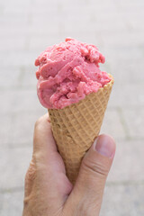 A waffle with a scoop of strawberry ice cream in hand