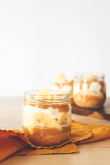 homemade banoffee pie in a glass cup on wooden table background.