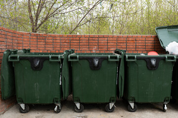 Three green trash bins in a dedicated area.