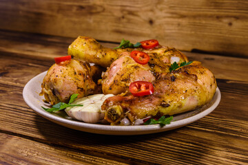 Baked chicken legs with parsley, garlic and sliced red hot pepper in a plate