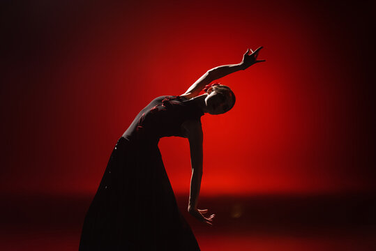 silhouette of young and attractive woman dancing flamenco on red