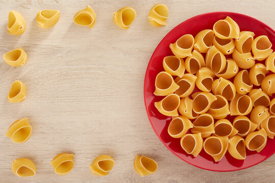 Raw pasta on a red plate, top view, copy space