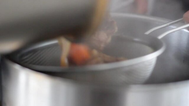 Close up of a Chef straining chicken stock