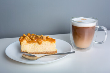 Latte coffee with a piece of cheesecake with caramel and peanuts coating