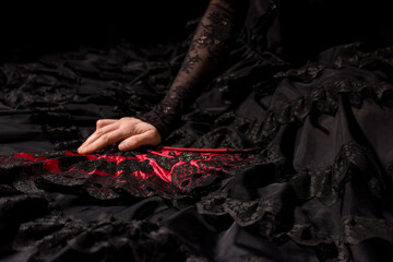 cropped view of young flamenco dancer in dress holding fan isolated on black