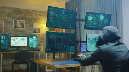Bearded cyber criminal wearing a hoodie while hacking government security. Dangerous malware.