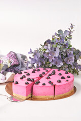 Round sliced pink blueberry cake on the lilac background colors