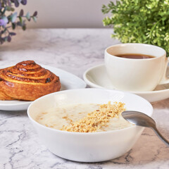 Breakfast of oatmeal and tea with a bun on the background colors