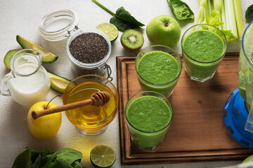 Green drink from green vegetables on a light stone background, close up