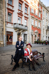 Obraz premium Adult married couple sits on a bench against the background of the old city.