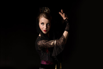 pretty young dancer looking away and dancing flamenco isolated on black