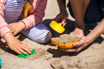 Happy father and daughter play in sand on the beach.