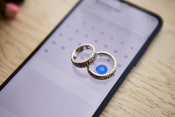 Wedding rings lie on the phone. Different accessories of businessman for creating style of  people on  wooden background