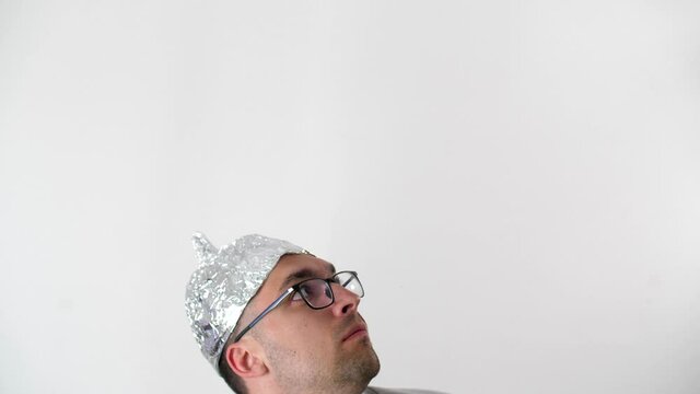 Frightened man in a tinfoil hat waved off the 5G waves.5G tower radiation protection. Irrational fear of a non-existent problem. Protective foil helmet to the brain from aliens.