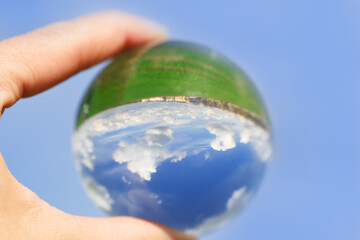 cloudy sky which is reflected in a Lens Ball.Horizon, green field. the world is upside down, on the...