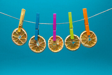 dry oranges on colors clothes peg isolated on aquamarine background