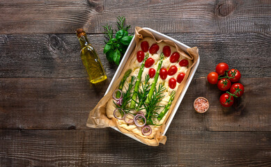 Sourdough preparing to bake trendy art garden focaccia bread on the wooden table, with ingredients. Copy space, top view.