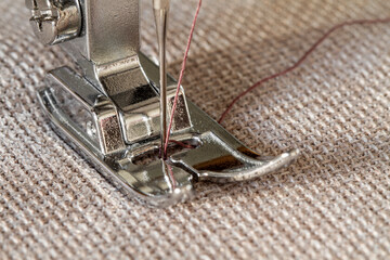 Closeup of sewing machine working part with beige fabric