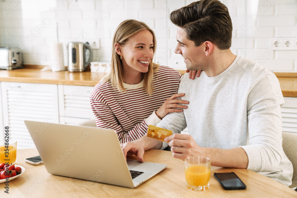 Poster Portrait of happy couple using laptop and holding credit card