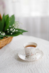 lilies of the valley in the basket and a cup of tea