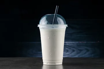 Fototapete Rund vanilla milkshake in plastic glass on a dark background. vanilla milkshake in takeaway cup © smspsy
