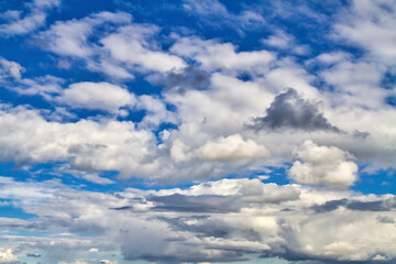 Cloudscape. Blue sky and grey clouds. Sunny day. Cumulus clouds.