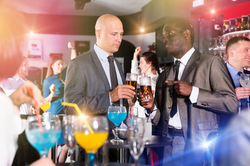 African and Caucasian men talking on corporate party