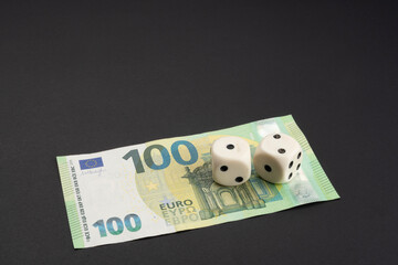 Money, finance and gambling concept: On bottom of frame 100 (hundred) EUR, Euro banknote. Two white dice on top showing the numbers 1 and 2. Black background with copy space