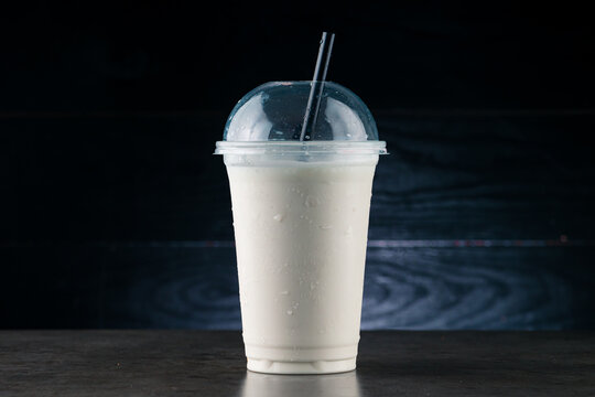 vanilla milkshake in plastic glass on a dark background. vanilla milkshake in takeaway cup
